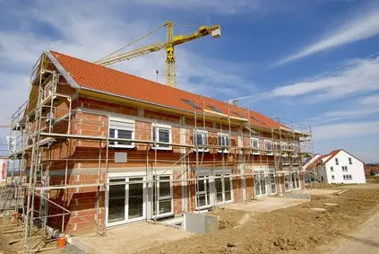 Baustelle eines Neubaus mit Gerüst und Kran für eine professionelle Baureinigung durch Gebäudereinigung Reischl